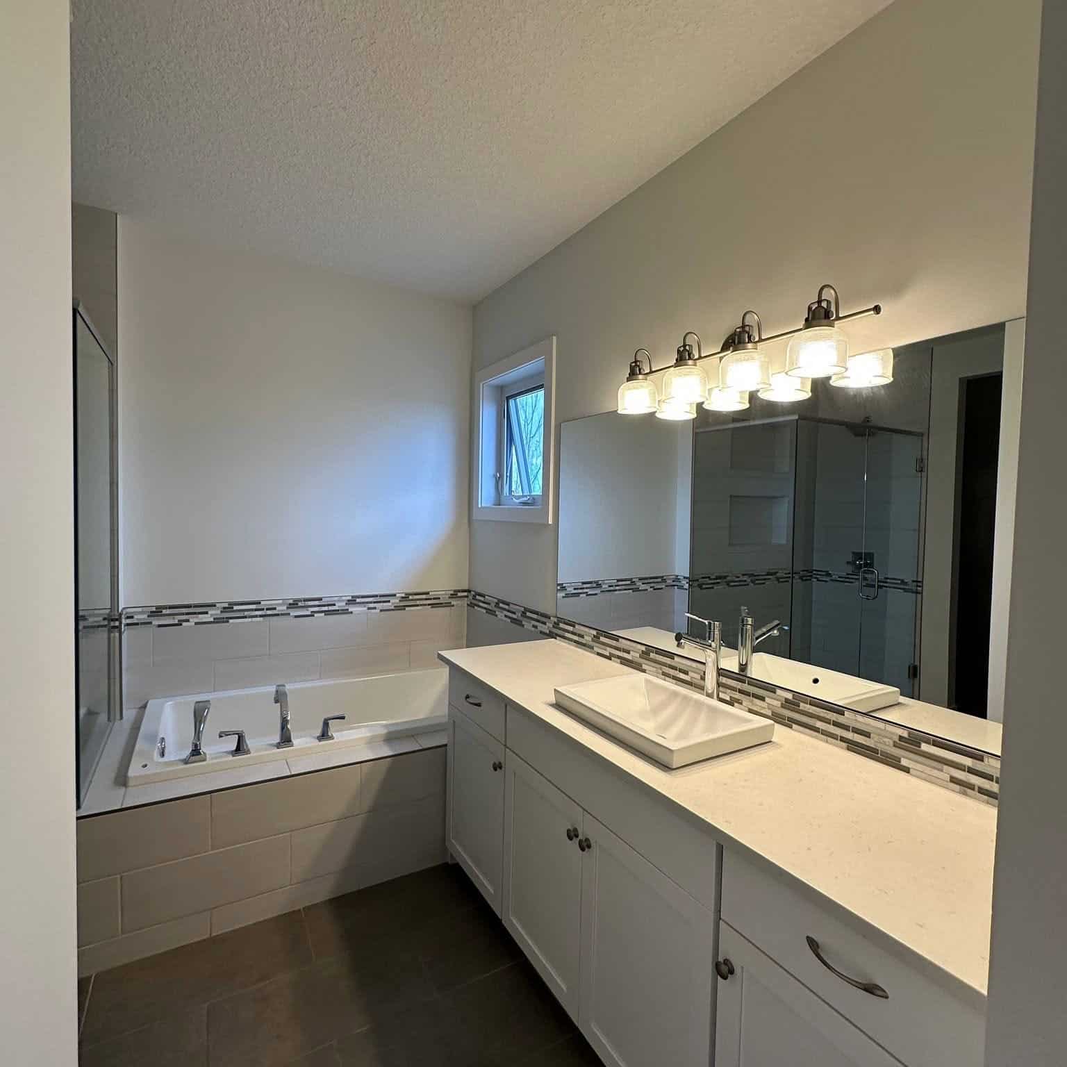 Contemporary bathroom featuring freshly painted neutral walls, white vanity, vessel sink, and a large mirror.