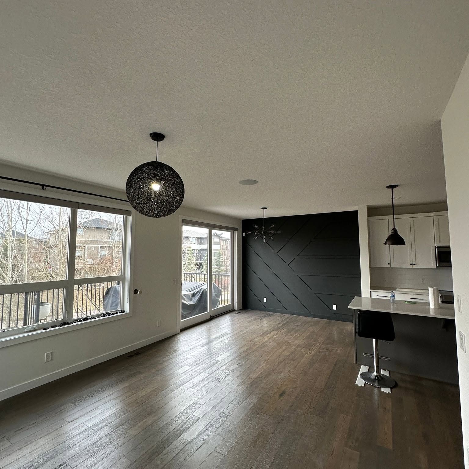 Contemporary living space featuring a bold black geometric accent wall and light neutral surrounding walls.