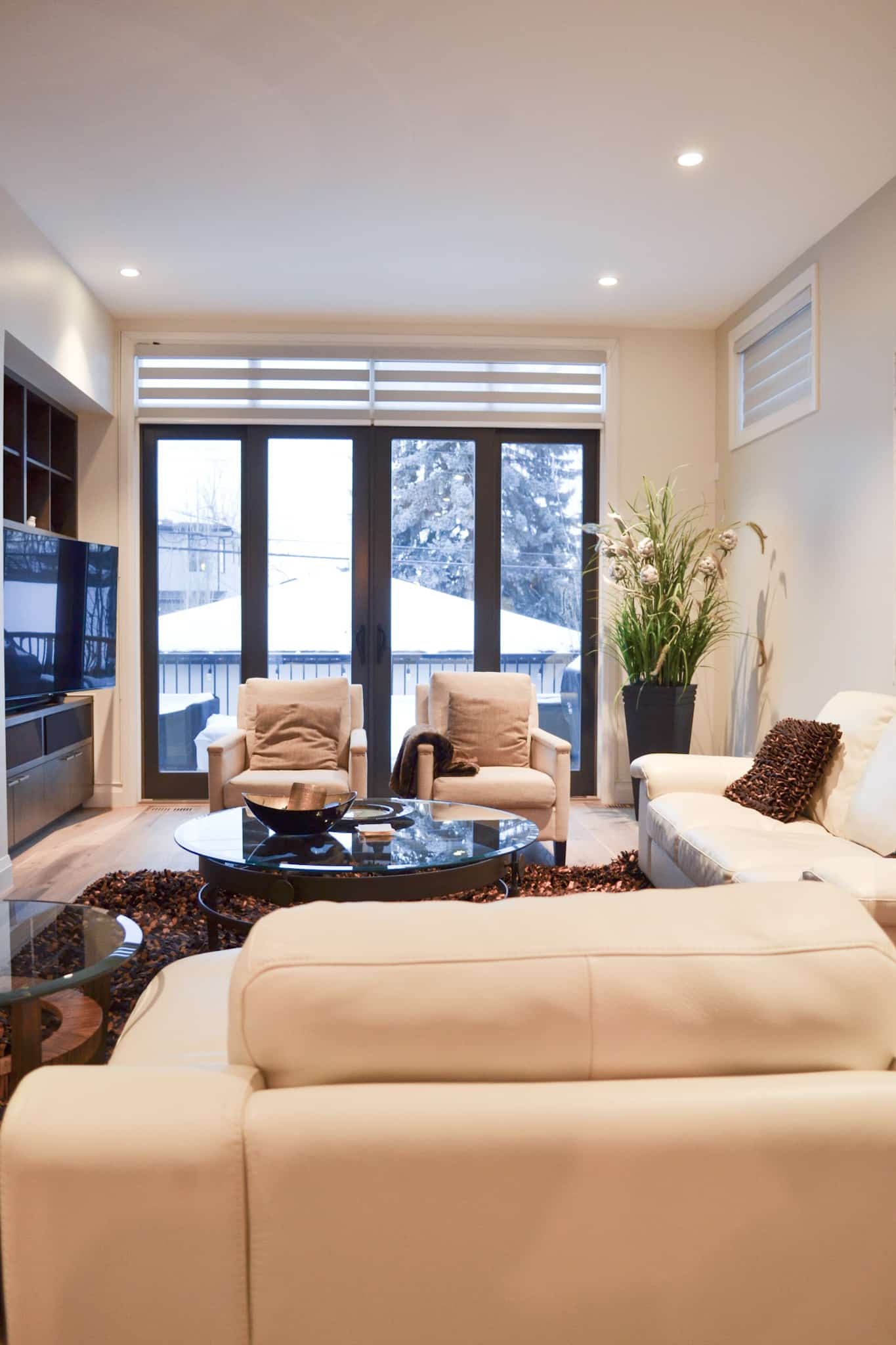 A spacious living room with freshly painted light beige walls, white sofas, and large windows overlooking a snowy landscape.