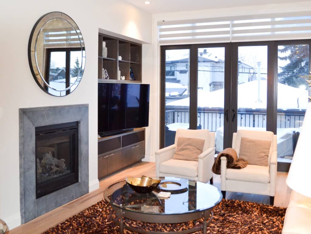 A stylish living room featuring a modern fireplace with a gray surround, a large mirror, and clean white painted walls.