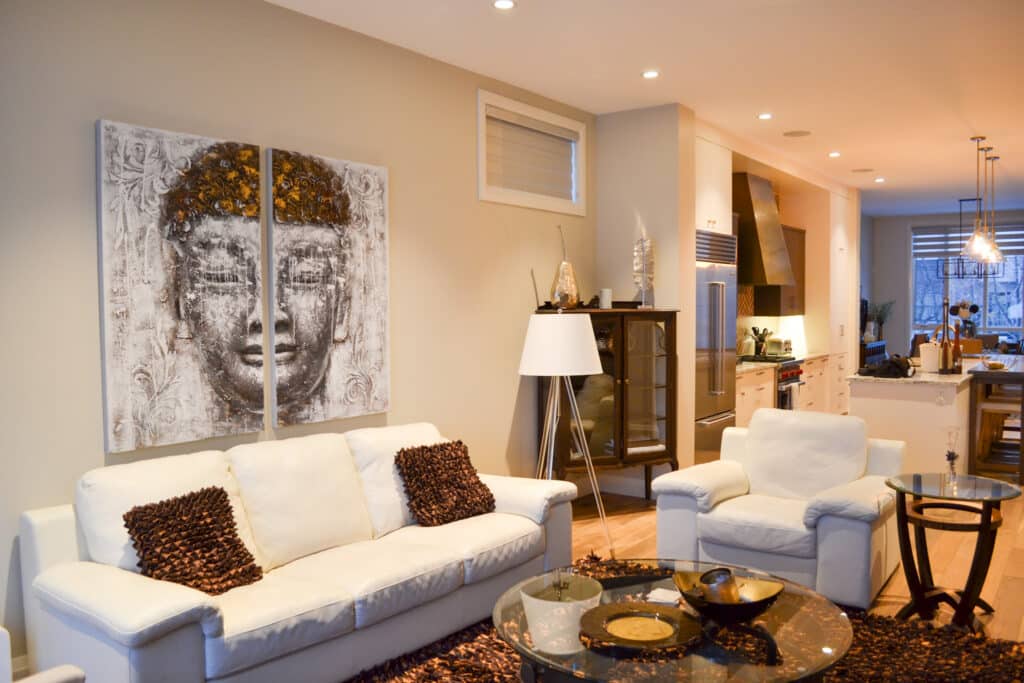An open concept living room and kitchen area with light beige painted walls and comfortable white furniture.